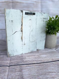 a small potted plant sitting on top of a wooden table next to a white board