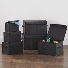 four black storage boxes sitting on top of a wooden floor