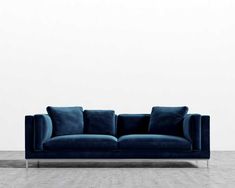 a blue couch sitting on top of a hard wood floor next to a white wall