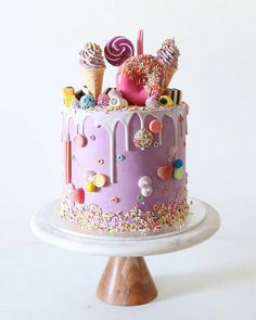 a purple cake with sprinkles, candies and lollipops on top