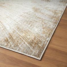 a beige and white area rug on a wooden floor with light colored wood grains