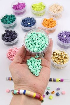 a hand holding a small container filled with beads and crayons next to other items