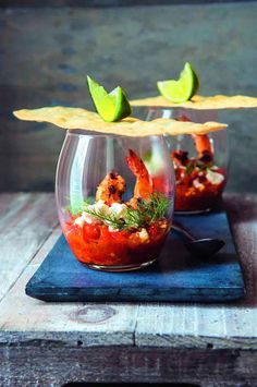 two glass bowls filled with food and garnished with lime wedges on top