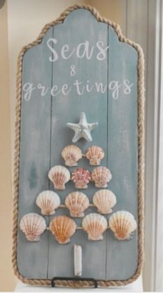 seashells and starfish are arranged on a wooden sign that reads seas & greetings