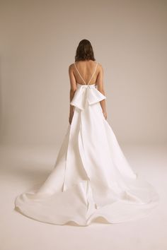 the back of a woman's wedding dress with a bow at the waist and straps