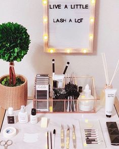 a table topped with lots of makeup and other items next to a sign that says live a little, lashes a lot