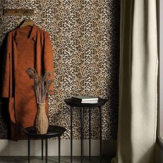 a leopard print wallpaper in a room with two small tables and a coat rack