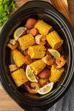 the crock pot is filled with shrimp, corn on the cob and potatoes