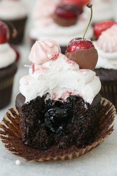 chocolate cupcakes with cherries and whipped cream on top