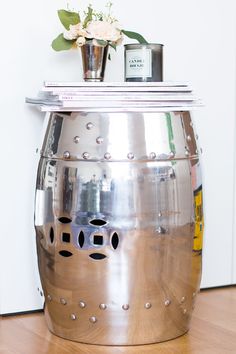 a large metal pot sitting on top of a wooden floor next to a vase with flowers