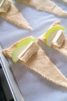 an apple slice is cut in half and placed on top of some crackers that are sitting on a baking sheet