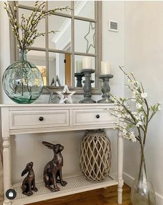 a white console table with two rabbits on it and a large mirror above the top