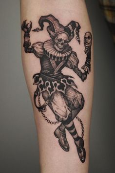 a black and white tattoo of a clown with chains on his legs, holding a skull