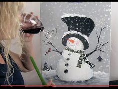 a woman is painting a snowman with red wine in front of the canvas on the wall