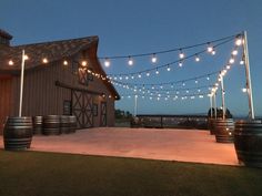 an outdoor venue with string lights and barrels