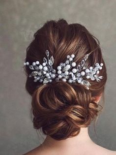 a woman wearing a bridal hair comb with pearls and leaves on it's head