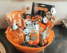 an orange bowl filled with halloween items on top of a table