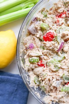 a bowl filled with tuna salad next to a lemon and celery