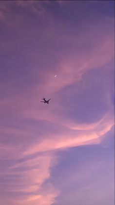 an airplane is flying high in the sky at sunset or dawn with some clouds behind it