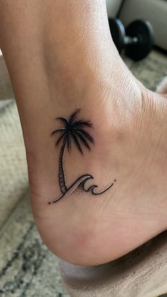 a small palm tree tattoo on the left side of the foot, with waves coming up behind it