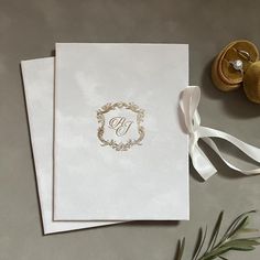 two wedding cards with the letter b on them next to some flowers and ribbon tied around it