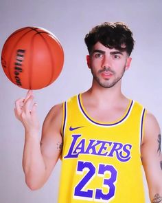 a man holding a basketball in his right hand and wearing a yellow jersey with the number 23 on it