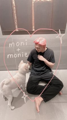 a man kneeling down next to a white dog and holding a pink heart shaped frame