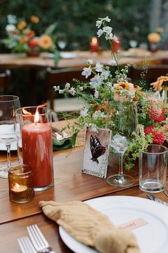 the table is set with flowers and candles for an outdoor dinner party or wedding reception