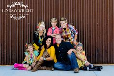 a family posing for a photo in front of a wall with the words lindsey wright photography