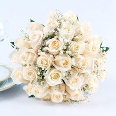 a bouquet of white roses sitting on top of a table