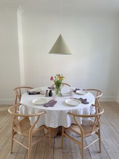 a table with plates and flowers on it in the middle of a wooden floored room