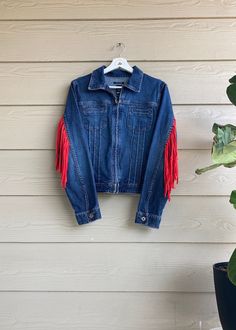 "This is a secondhand, one-of-a-kind denim jacket with a handmade zero-waste fringe sewn onto the back and sleeves, making this item completely upcycled and unique! Features a zipper closure and front pockets. Spot treat, or wash inside out and lay flat to dry. Listed size is a Large but more accurately fits up to a smaller Medium; modeled on a size Small. Measurements when zipped- Bust: 38\" Hip: 36\" Length: 21\" **This product helps to minimize textile waste in the fashion industry by using only secondhand materials, some unfit for resale. Due to the item's secondhand nature, there may be light signs of wear. Repairs are covered by The Uncommon Closet for the lifespan of the garment." Fall Festival Denim Jacket With Fringe, Fringe Denim Jacket For Fall Festival, Fall Festival Fringe Denim Jacket, Denim Outerwear With Frayed Hem For Festival, Festival Denim Fringe Outerwear, Fringe Cotton Denim Jacket For Fall, Fall Cotton Denim Jacket With Fringe, Fall Fringe Cotton Denim Jacket, Festival Denim Jacket With Fringe And Long Sleeves