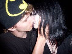 a man and woman kissing each other while wearing beanies with the word batman written on them