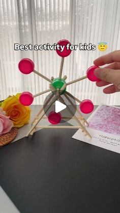 a person is making a model with pops and glue on top of a table next to flowers