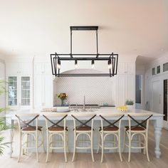 a kitchen with white cabinets and an island in the middle, surrounded by stools