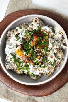 a white bowl filled with food on top of a wooden plate