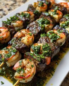 steak and shrimp kabobs with chimica sauce on a white platter