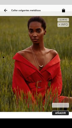 a woman in a red dress is sitting in tall grass and looking at the camera