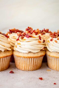 several cupcakes with white frosting and bacon on top are lined up in a row