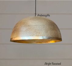 a gold colored light hanging from a ceiling with an arrow pointing to the top and bottom