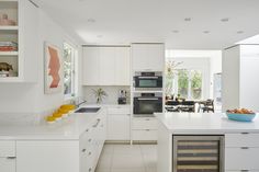 a large kitchen with white cabinets and counter tops is pictured in this image, there are fruit on the counter