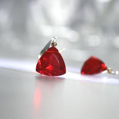 Introducing our exquisite red trillion-cut AAA quartz earrings, designed to captivate with their vibrant, fiery hue. Each gemstone features a brilliant red ruby quartz, complemented by a subtle gold hematite accent that adds a touch of warm sparkle. The stones are meticulously set to highlight their stunning clarity and rich color, making them the perfect statement pieces for any occasion. The earrings are elegantly suspended from modern, slightly hammered sterling silver ear wires, which lend a sleek and contemporary edge. These earrings blend delicate beauty with bold color, offering a chic and effortless way to add a pop of glamour to your look. Ideal for those who appreciate understated elegance with a hint of luxury. Quartz Trillions are 12mm  (Lab Created) Earrings measure about 1 an Party Red Gemstone Earrings, Red Gemstone Earrings For Valentine's Day, Red Sterling Silver Earrings For Evening, Red Sterling Silver Evening Earrings, Red Ruby Gemstone Earrings, Ruby Quartz, Silver Gold Earrings, Red Quartz, Color Making