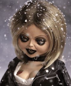 a creepy doll wearing black and white makeup with snow falling on her head, in front of a gray background