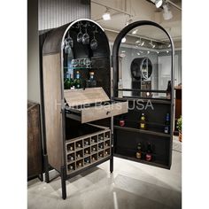 an open cabinet with wine glasses and bottles on it in the middle of a room