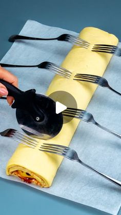 a person holding forks and knifes over a roll of food wrapped in napkins