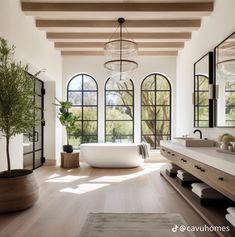 a large bathroom with an oval tub and double sinks in the center, surrounded by arched windows