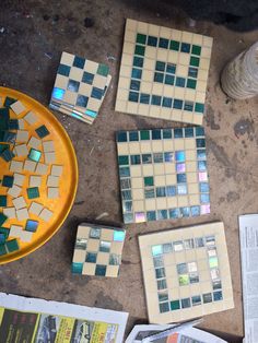 several pieces of mosaic tile sitting on top of a table next to a yellow plate