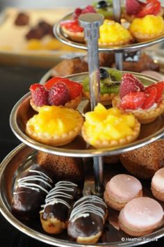 three tiered trays filled with different types of pastries and fruit on them