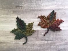 two crocheted leaves are sitting on a table