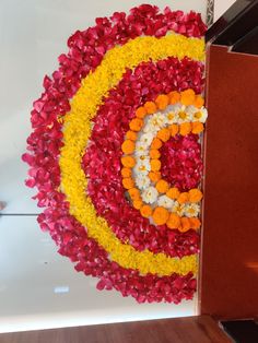 an arrangement of flowers arranged in the shape of a spiral on a white surface with red, yellow and orange petals